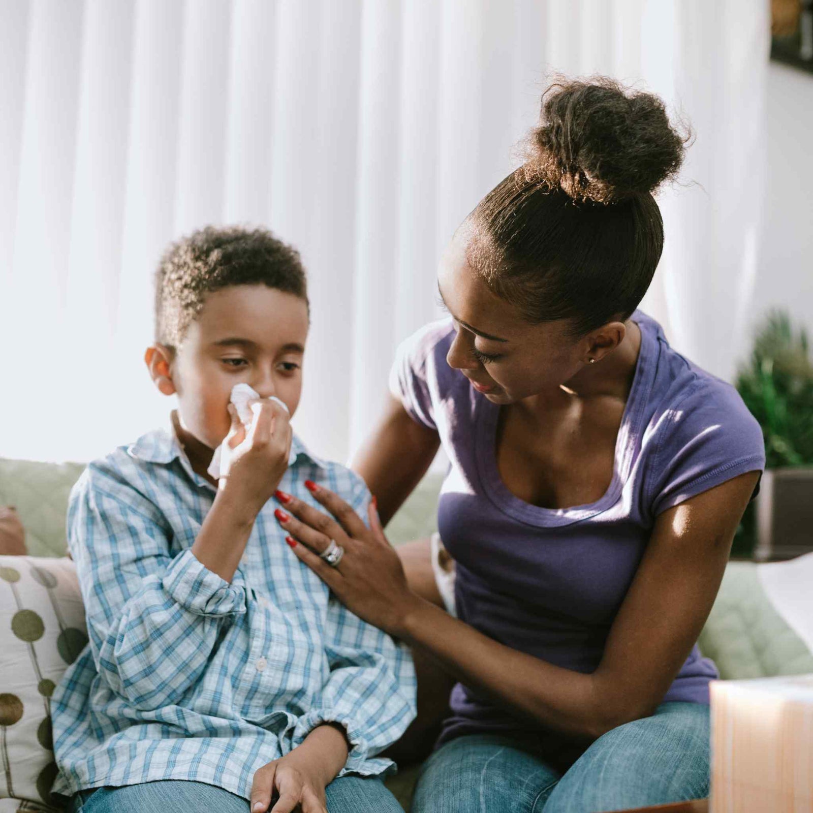 child blowing nose being comforted by mom