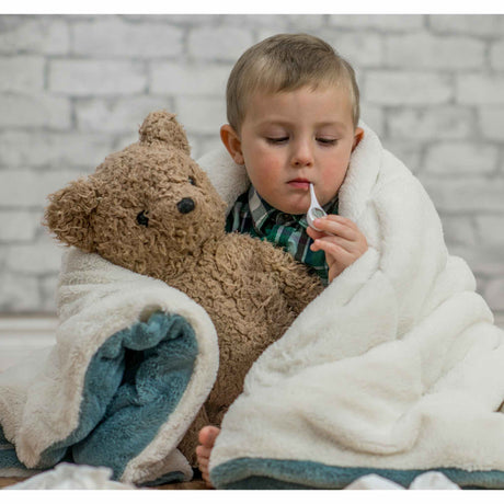 sick child with thermometer and teddy bear