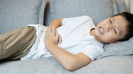 kid laying on couch holding stomach