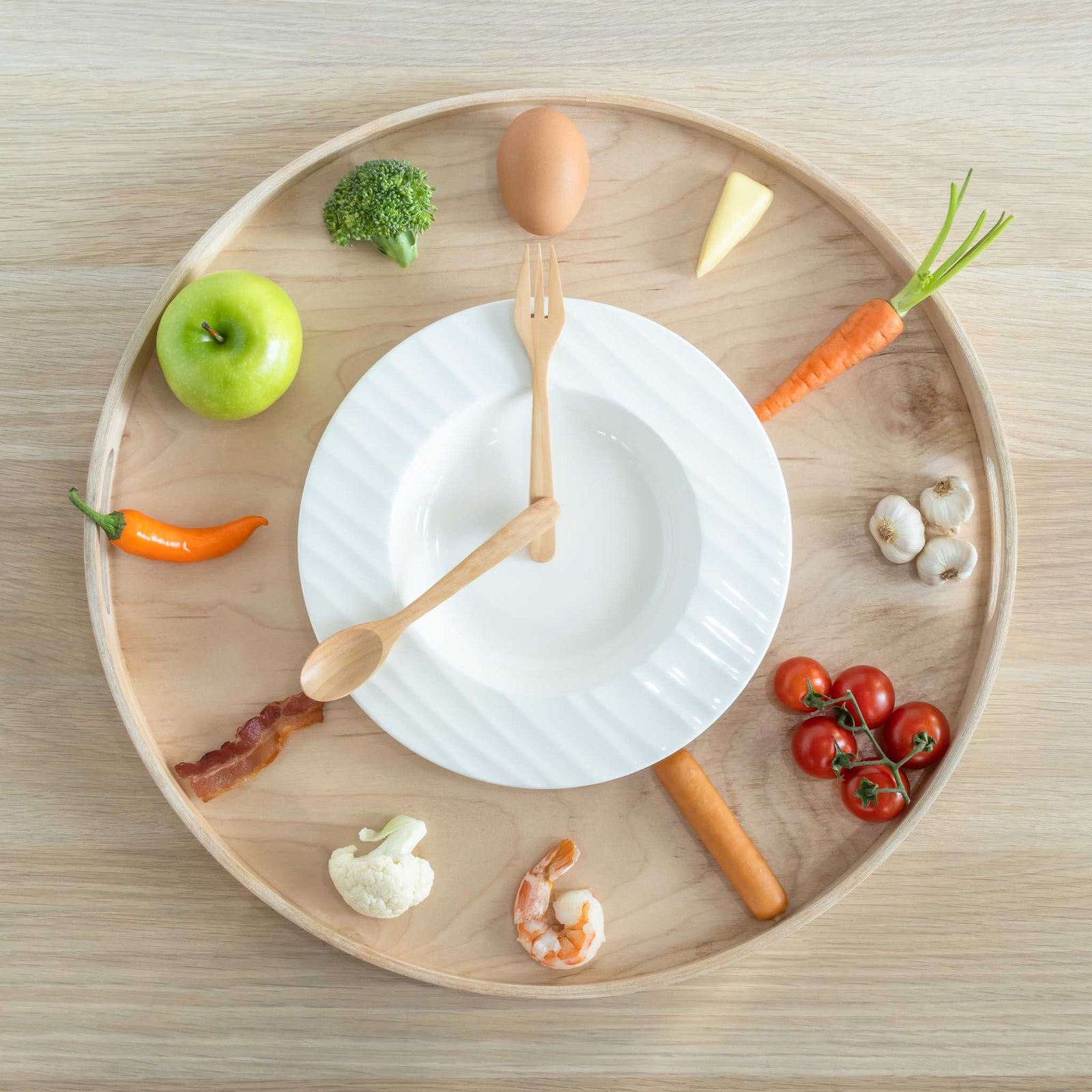 plate with spoons set up as clock hands and vegetable as hours