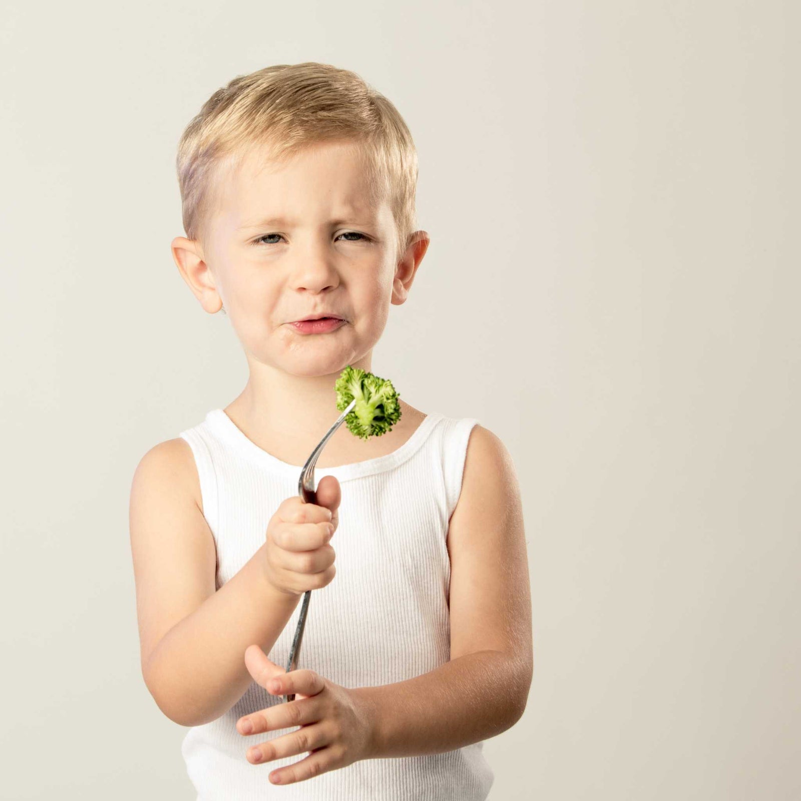 unhappy child holding broccoli on a fork 