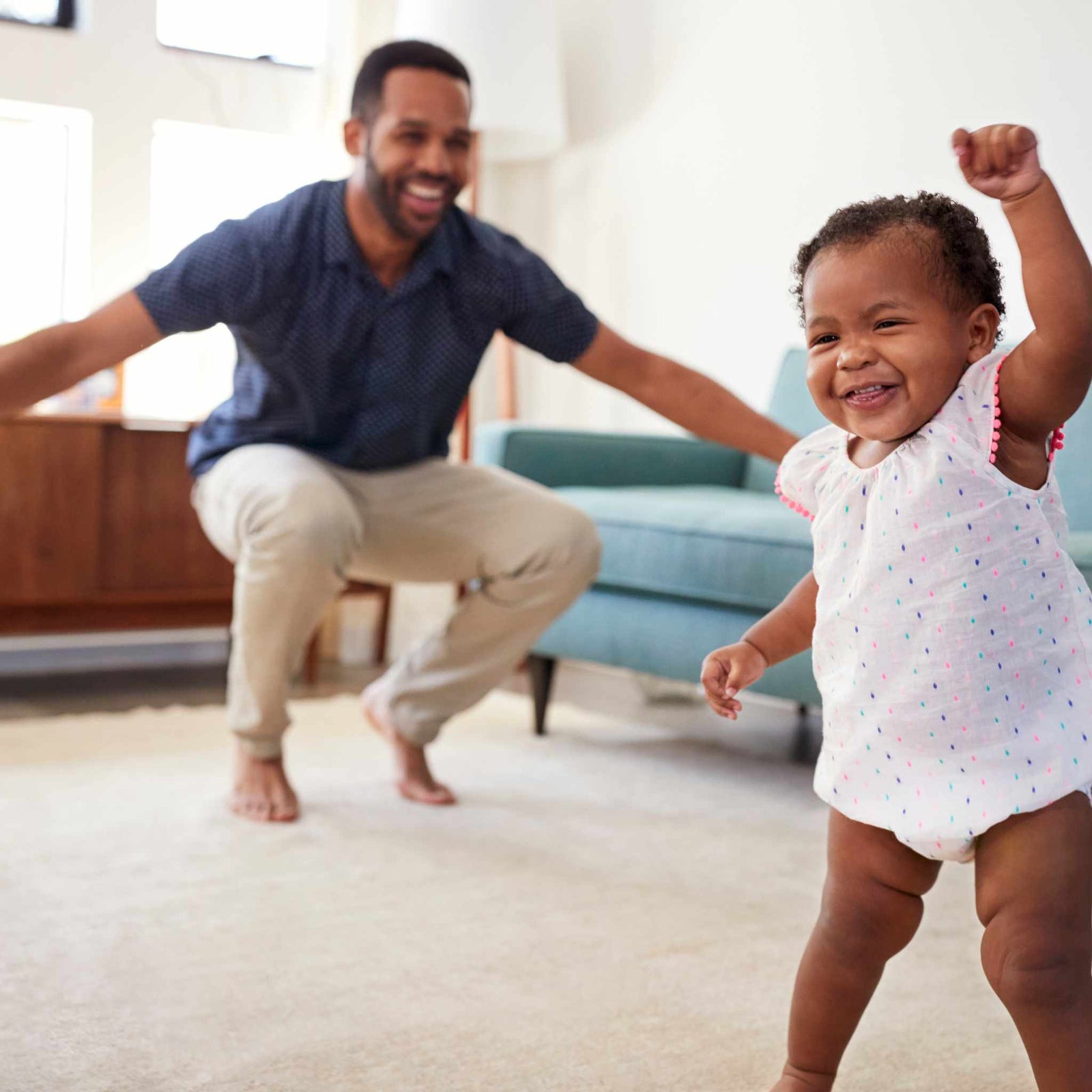 dad cheering on baby's first steps