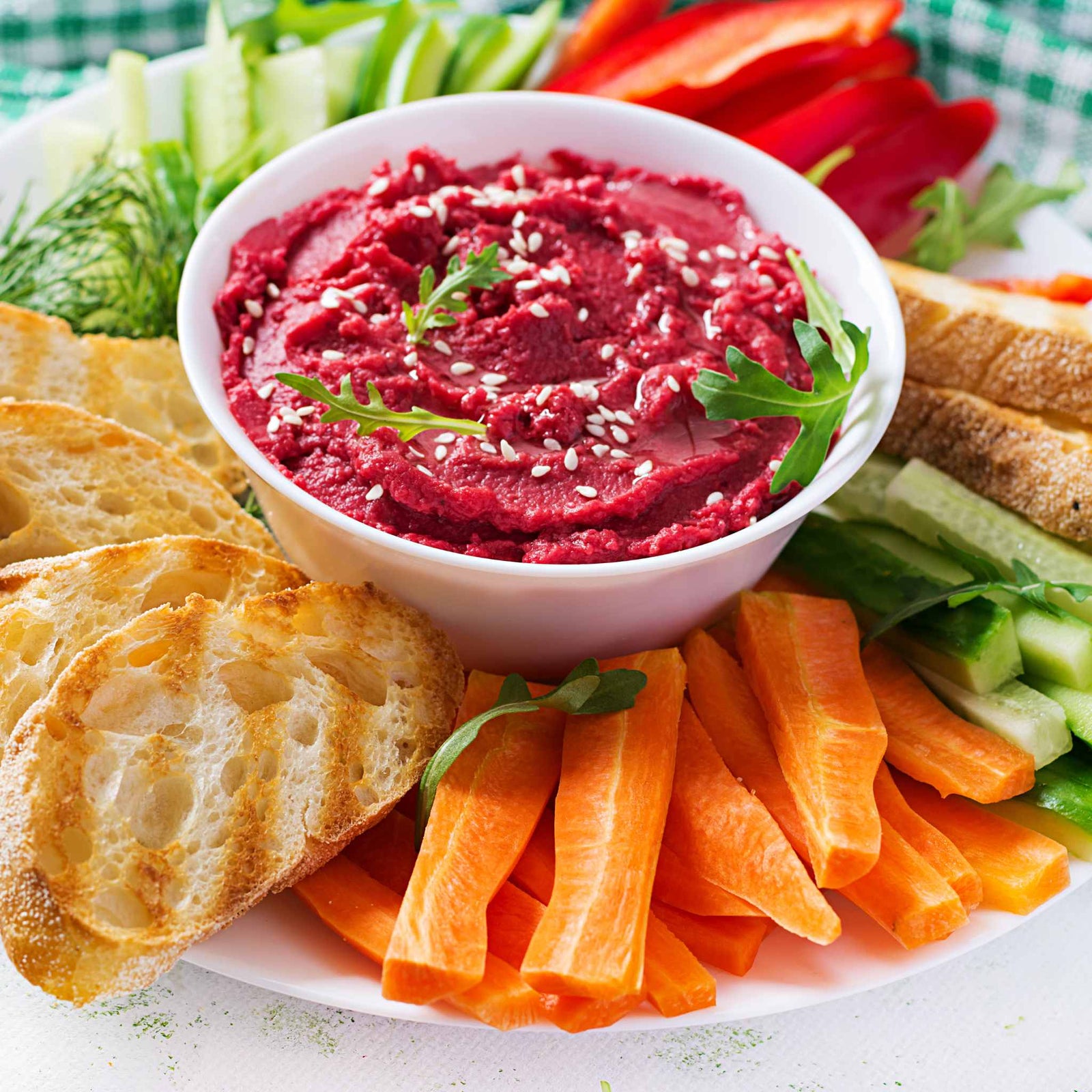 beet hummus surrounded by healthy snacks