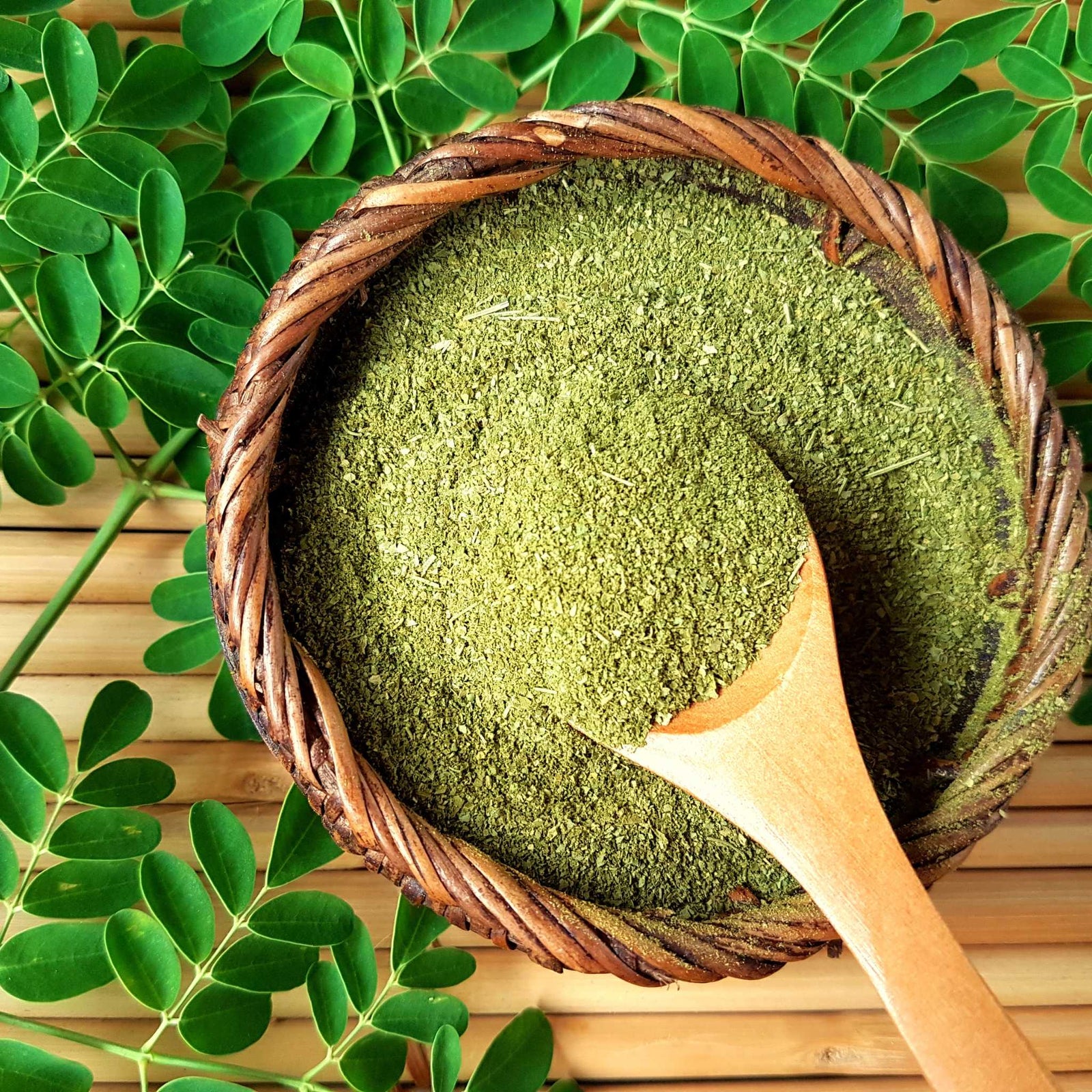 Green powder in a bowl with a wooden spoon