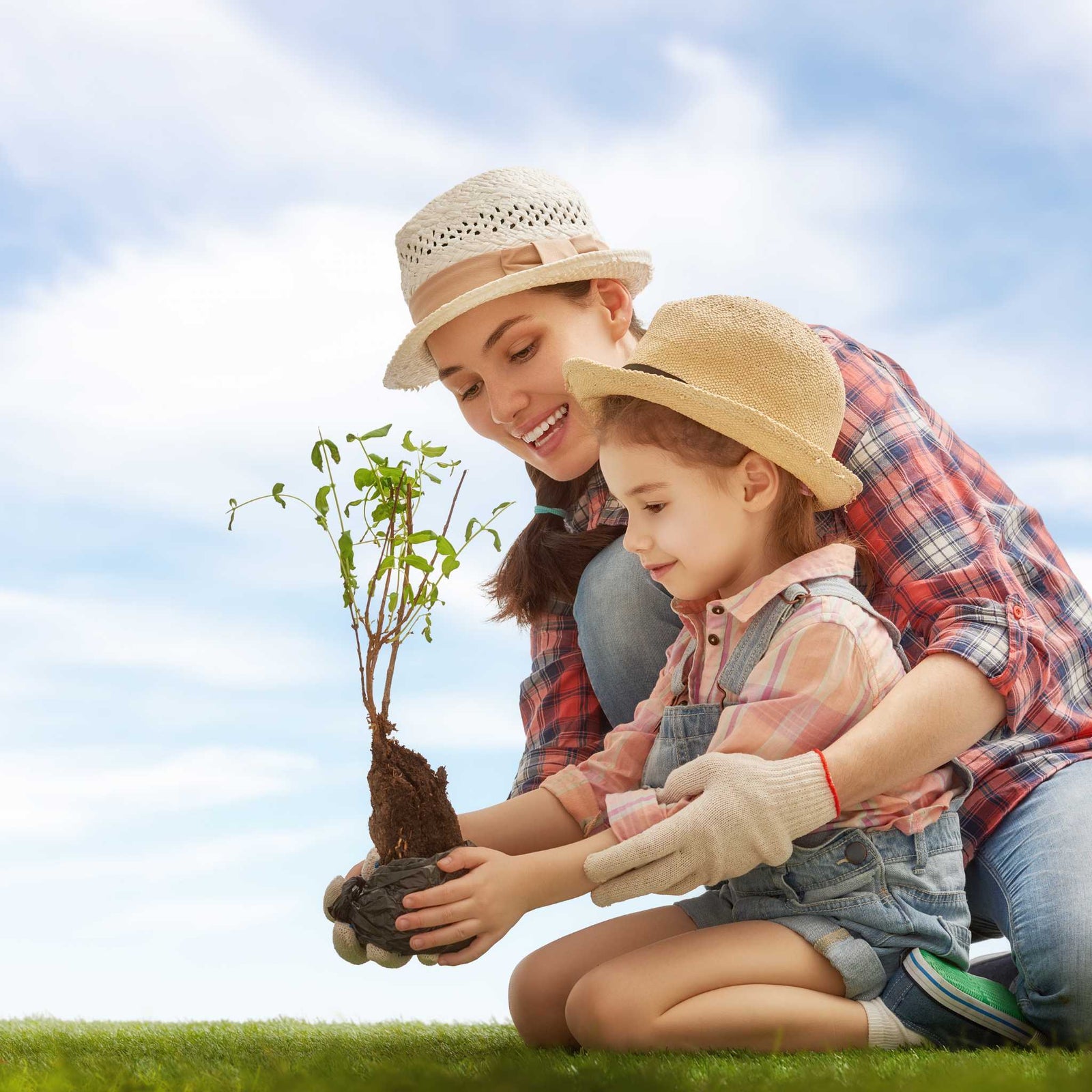 mom planting small plant with child