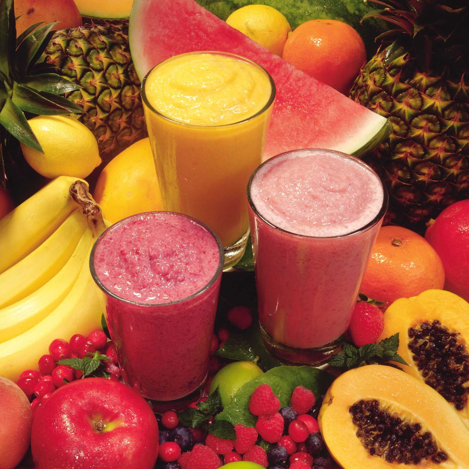 cups of smoothies surrounded by fruits and vegetables