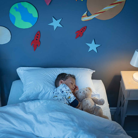 child sleeping in bed in room decorated like space
