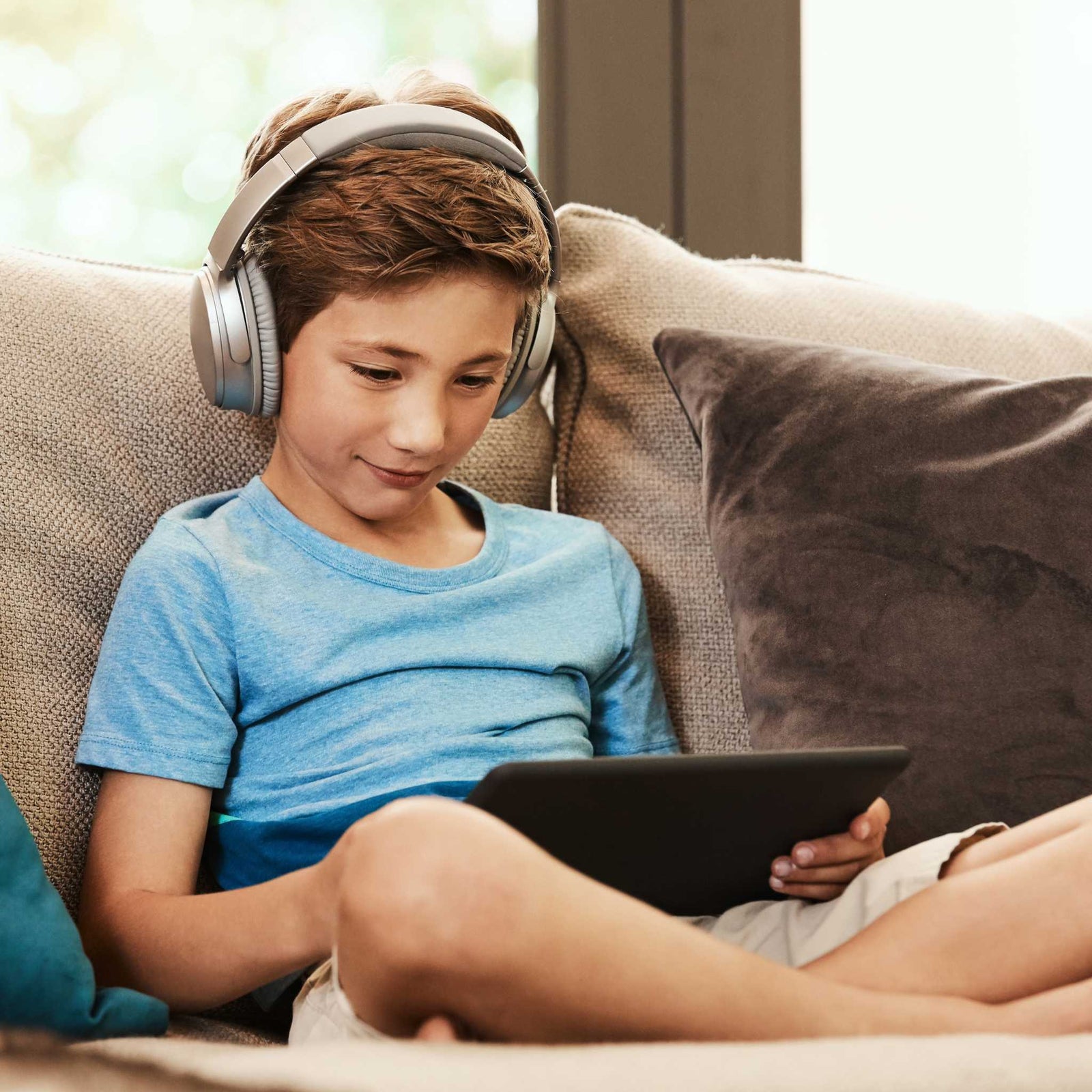 kid sitting on couch with tablet and headphones