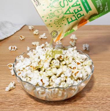 Sprinkling Easy Peasie veggie powder Green Blend pouch onto popcorn